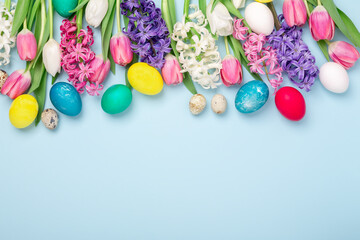 Obraz premium Easter composition. Multicolored easter eggs, tulips and hyacinths on blue background. Easter concept. Copy space