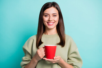 Photo portrait of positive woman drinking tea on break holding red mug isolated on vivid cyan colored background