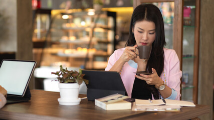 Businesswoman relaxing with coffee and smartphone while working in cafe