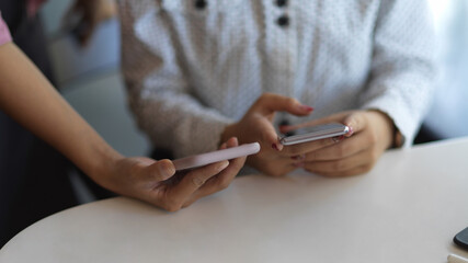 Two people using two smartphone to consulting on their project in office room