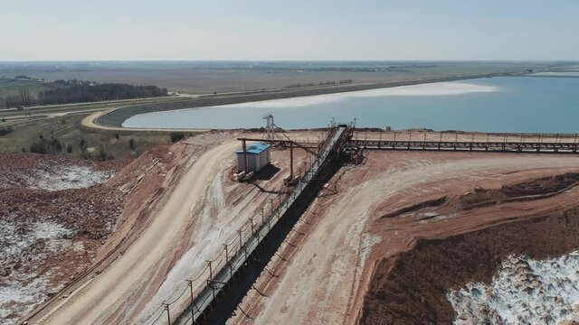 Mining of potash salt, conveyor line in salt pits, aerial view of salt piles and industrial quarries, view from height on hills of sand, sludge and mining waste.