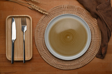 Wooden dinning table with mock up ceramic plate, cutlery, place mat and napkin
