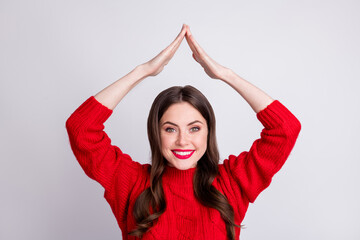 Photo portrait of smiling young woman keeping hands over head roof mortgage safety isolated on pastel grey color background