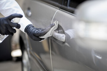 Car disinfecting service. Woman disinfecting and cleaning the inside handle of the car door. Safety and preventing infection of Covid-19 virus, contamination of germs or bacteria, wipe clean surfaces