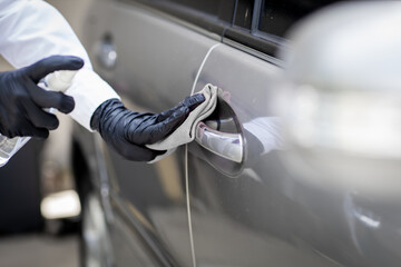 Car disinfecting service. Woman disinfecting and cleaning the inside handle of the car door. Safety and preventing infection of Covid-19 virus, contamination of germs or bacteria, wipe clean surfaces