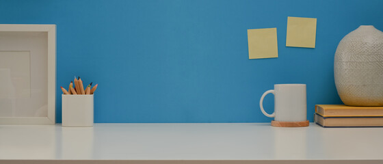 Worktable with copy space, stationery and decorations on white desk with blue wall background