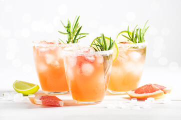 Three glasses with paloma cocktail with ice and tequila stand on a white wooden table. Horizontal orientation, selective focus