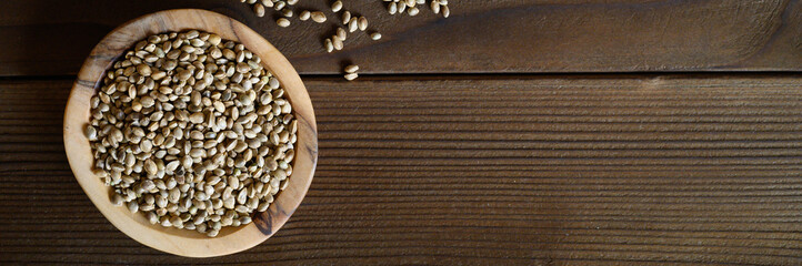 wooden rustic bowl with organic dried hemp food seeds. flat lay, space for text. banner