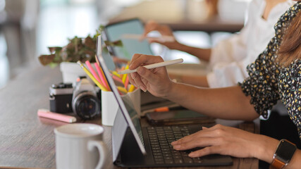 Fototapeta na wymiar Female hand holding stylus pen to work with digital tablet on worktable in meeting room