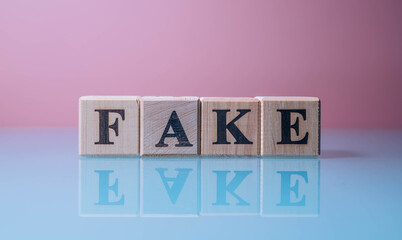 Text FAKE on wood cube blocks. The letters FAKE written on the cubes in black letters isolated on a...