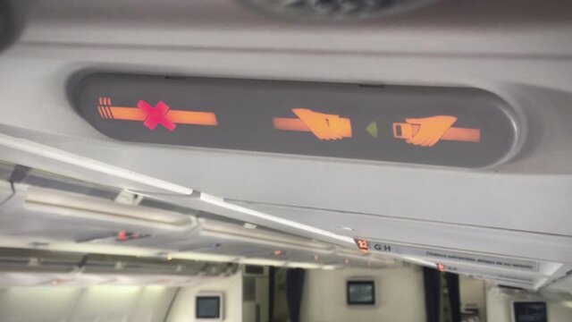 No Smoking and Fasten Seat Belt Sign on Board of a Passenger Aircraft. Close Up. 4K.