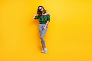 Fototapeta na wymiar Full length photo of attractive brunette young happy woman touch hair wear sunglass isolated on yellow color background