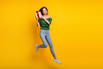 Fototapeta na wymiar Full length photo of curious happy young woman shake present box jump up air isolated on vibrant yellow color background