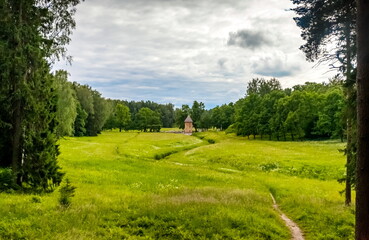 Summer landscape in a city Park with trees, a tower with a stone bridge, sky with clouds