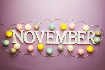 November alphabet letter with cotton ball LED decoration on purple background