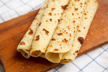 Homemade Norwegian Potato Flatbread (Lefse) with Butter and Sugar on a rustic wooden board on cloth, low angle view. Close-up.