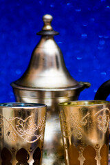 Group of teapot and glasses of oriental tea on a tray on blue background with glitter