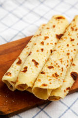 Homemade Norwegian Potato Flatbread (Lefse) with Butter and Sugar on a rustic wooden board on cloth, low angle view.