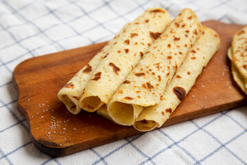 Homemade Norwegian Potato Flatbread (Lefse) with Butter and Sugar on a rustic wooden board on cloth, low angle view. Close-up.