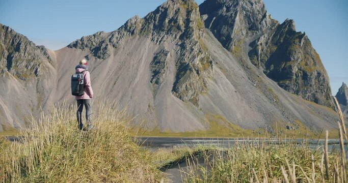 Morning scene of female traveler exploring Stokksnes cape with Vestrahorn (Batman Mountain) on background. Sunny summer day in Iceland