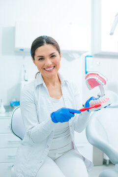 Friendly looking dentist demonstrating how to brush teeth correctly