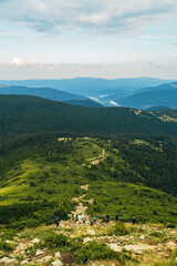 Obraz premium People descend down a large green mountain range. Mountain Hiking
