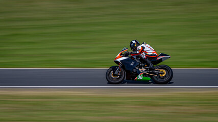 A panning shot of a racing bike cornering on a track.