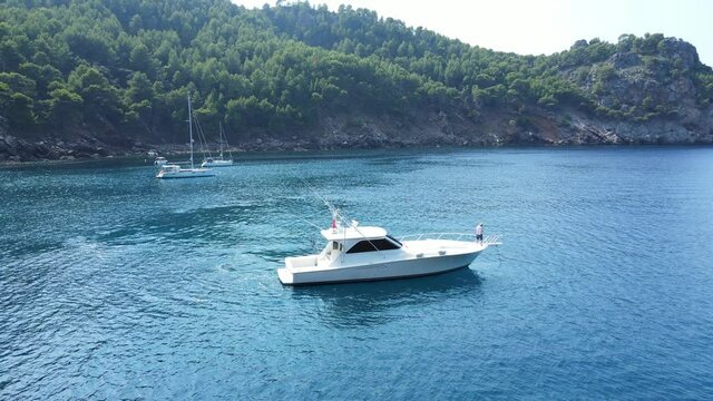man on the deck of a yacht casting anchor, tourism on the beaches of mallorca, spain with a boat in the mediterranean.
