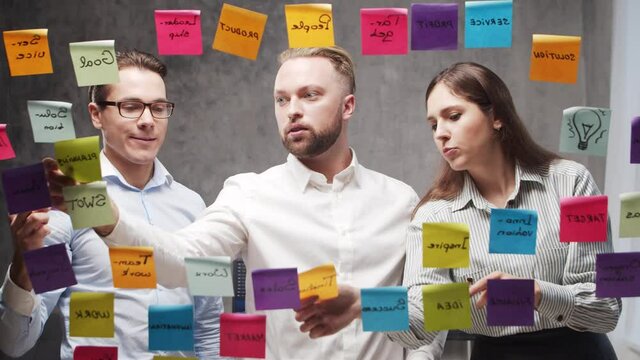 Timelapse of the business people doing brainstorm at a meeting using stickers on the glass. Team of office workers discussing strategy, business plan and goals. Startup concept.