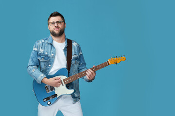 handsome man in denim with guitar isolated on blue background. copy space