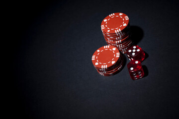 Red dice and poker chips. Studio photo isolated on black background. Selective focus on object.