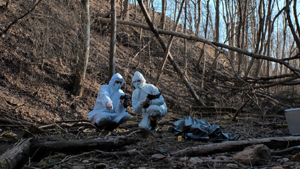 Detectives are collecting evidence in a crime scene. Forensic specialists are making expertise. Police investigation in a forest.