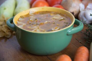 Minestrone soup, a typical thick vegetables soup, originally from Italy, served in a green bowl with Farfalle Pasta.  