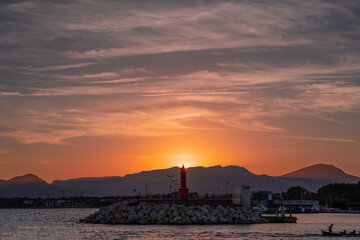 Fototapeta na wymiar puesta de sol sobre el faro del puerto de cambrils, tarragona