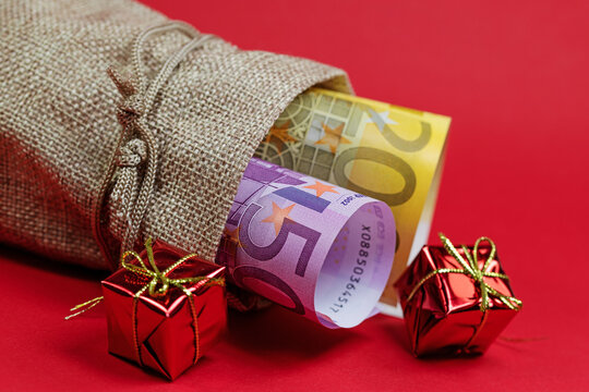 Geldscheine, Weihnachtsgeld im Jutebeutel vor rotem Hintergrund