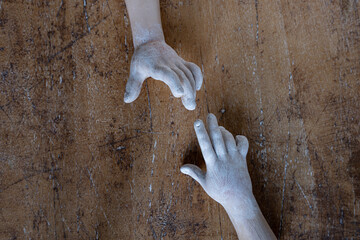 Doll hands trying to touch on a vintage wooden table. Concept of distance, desire and social...