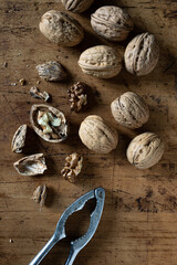Walnuts with and without shells
and nutcracker on wooden table. Top view