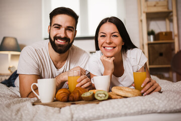 Obraz na płótnie Canvas Cute couple having breakfast in bed in the bedroom