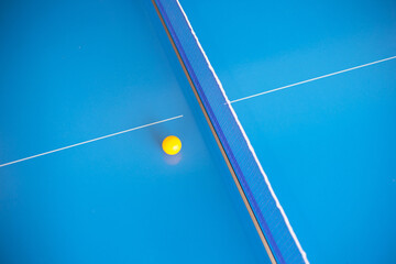 Net of table tennis ping pong with yellow ball on blue background.