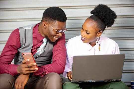 two business partners using a mobil phone and laptop