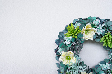 A wreath made of succulent plants decorates the interior of the modern apartment with a textured wall background