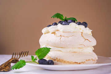 Pavlova meringue cake decorated with whipped cream and blueberries.  Healthy dessert. Homemade meringues cookies.