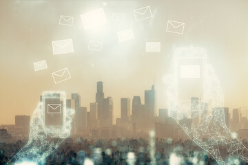 Double exposure of envelop hologram flying from gadget and city view background. Concept e-mail.
