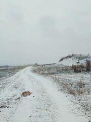 snowy road in the field near the old wooden fence of the farm