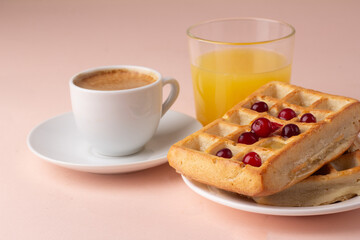 waffles with honey and berries black coffee for breakfast on a pink background close-up.