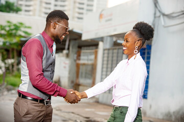  businessman and businesswoman shaking hands in the street