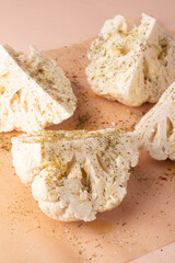 cauliflower with spices and herbs on baking paper close up.