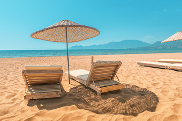 Sunbed and parasol on empty sandy beach during low season, or early in the morning. Sea and ocean...