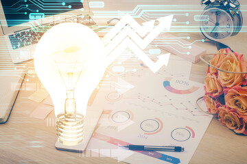 Computer on desktop in office with bulb icon hologram. Double exposure. Concept of idea.