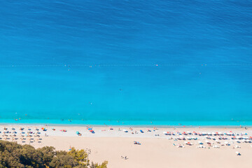 Aerial view of a white idyllic beach in a resort town washed by the bright turquoise Mediterranean sea